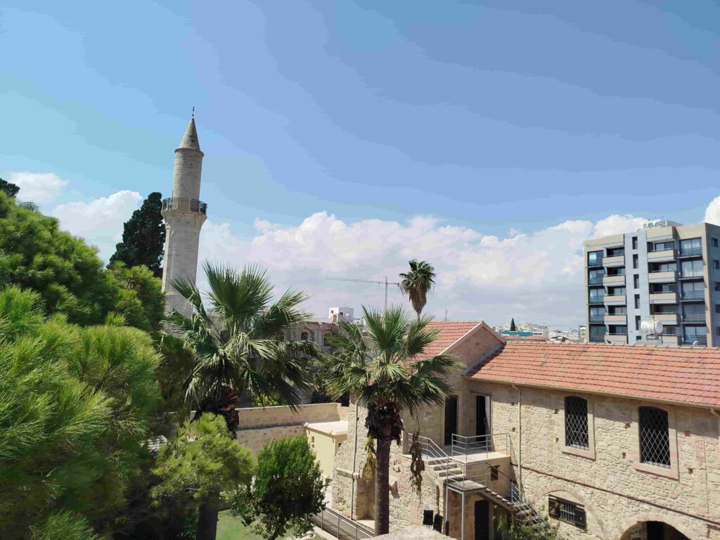 Ein Gebäude mit einem Turm und Bäumen in Larnaka