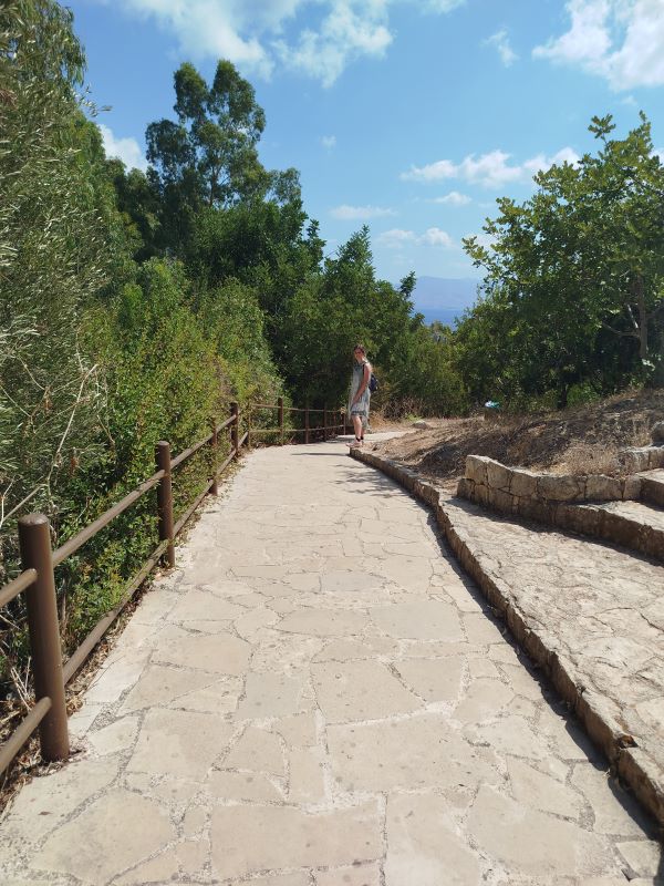 Eine Person, die auf einem Weg mit Bäumen und blauem Himmel in Zypern bei Paphos geht